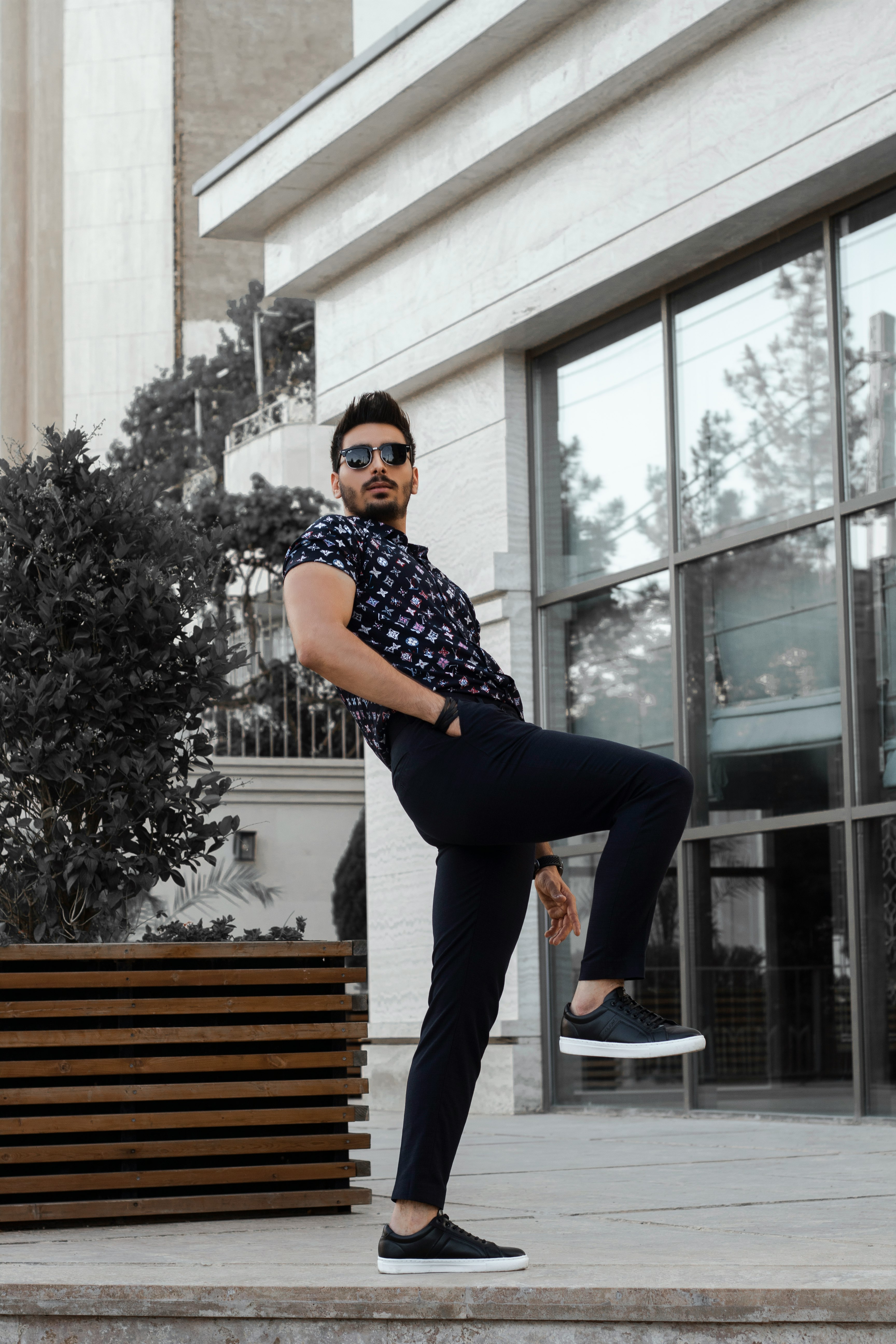 man in black and white checkered button up shirt and black pants standing on brown wooden